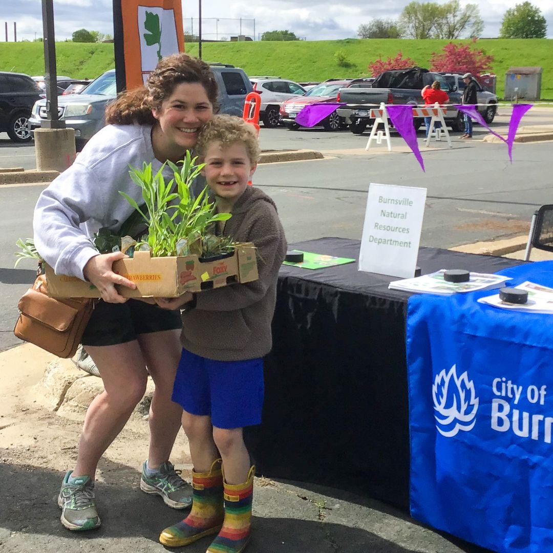 A mother and son holding their purchases at the Native Plant Market