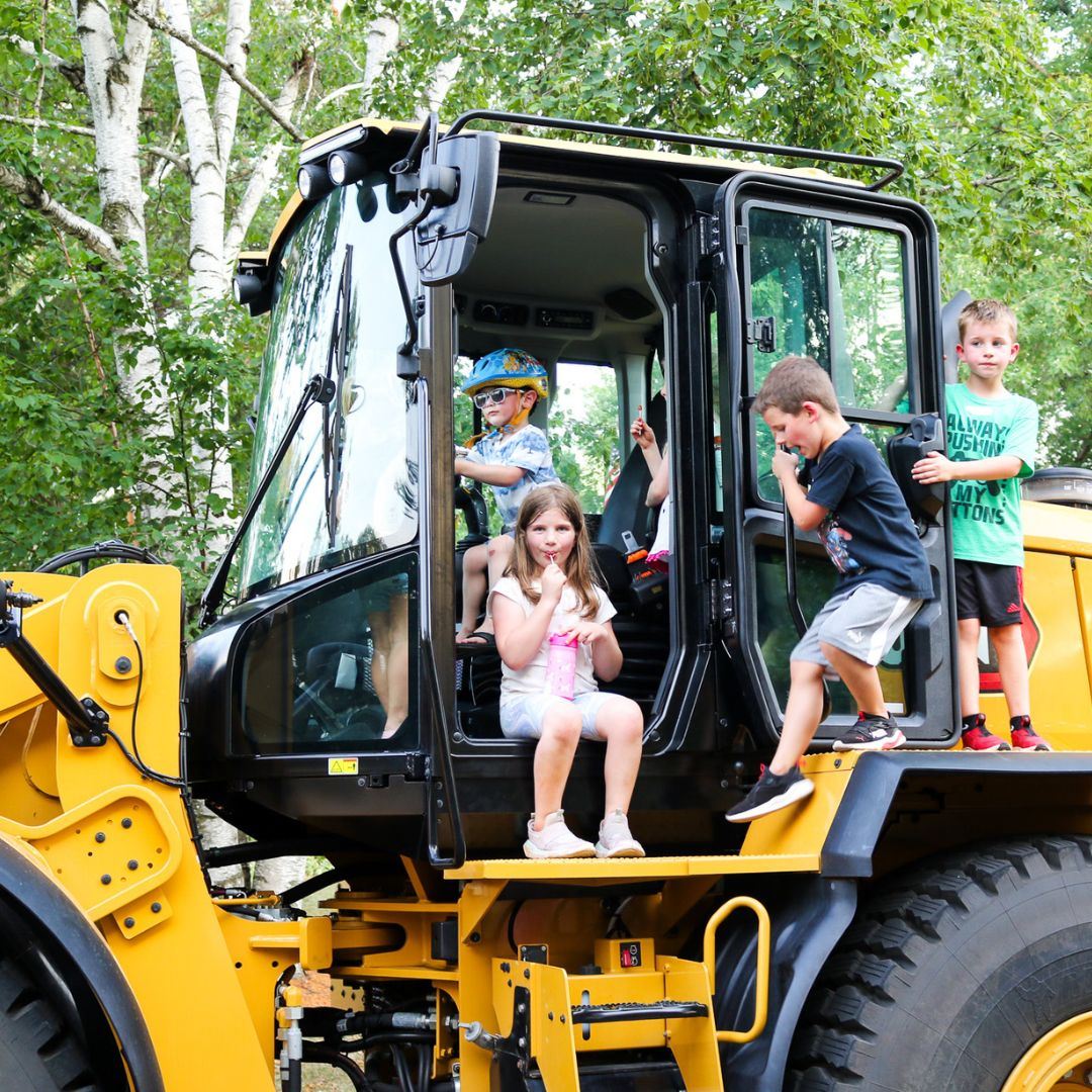 Five kids climbing on an excavator at a Night to Unite party