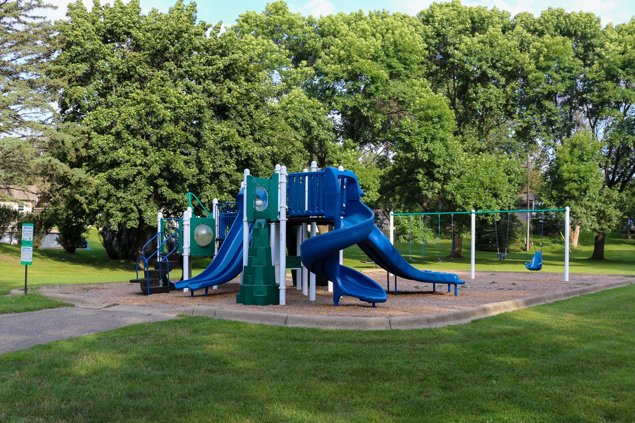 Arbor Park playground surrounded by grass and trees in the background
