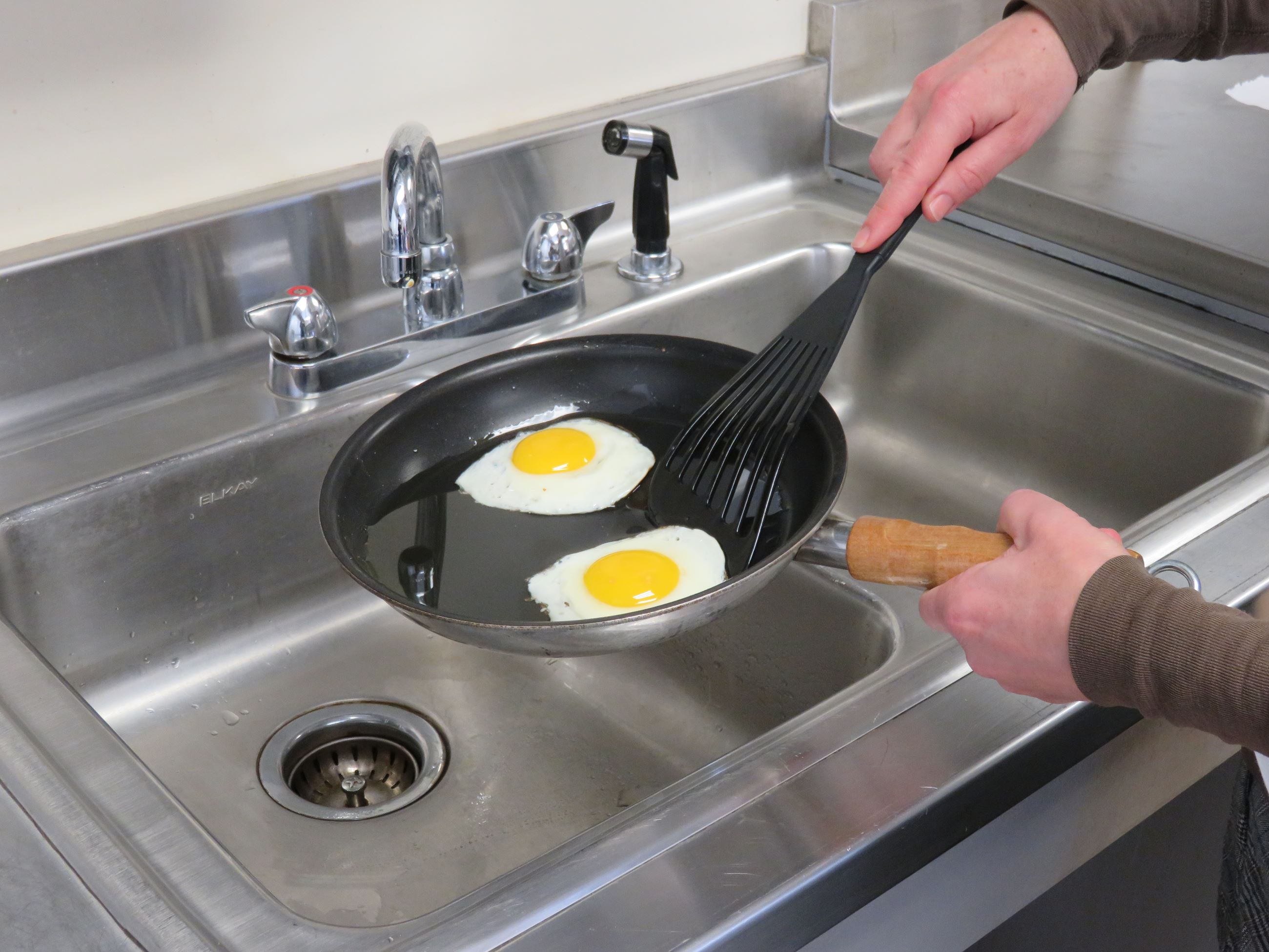Person about to put fried eggs into the sink to dispose of them.