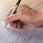 Hand holding pen filling out paperwork