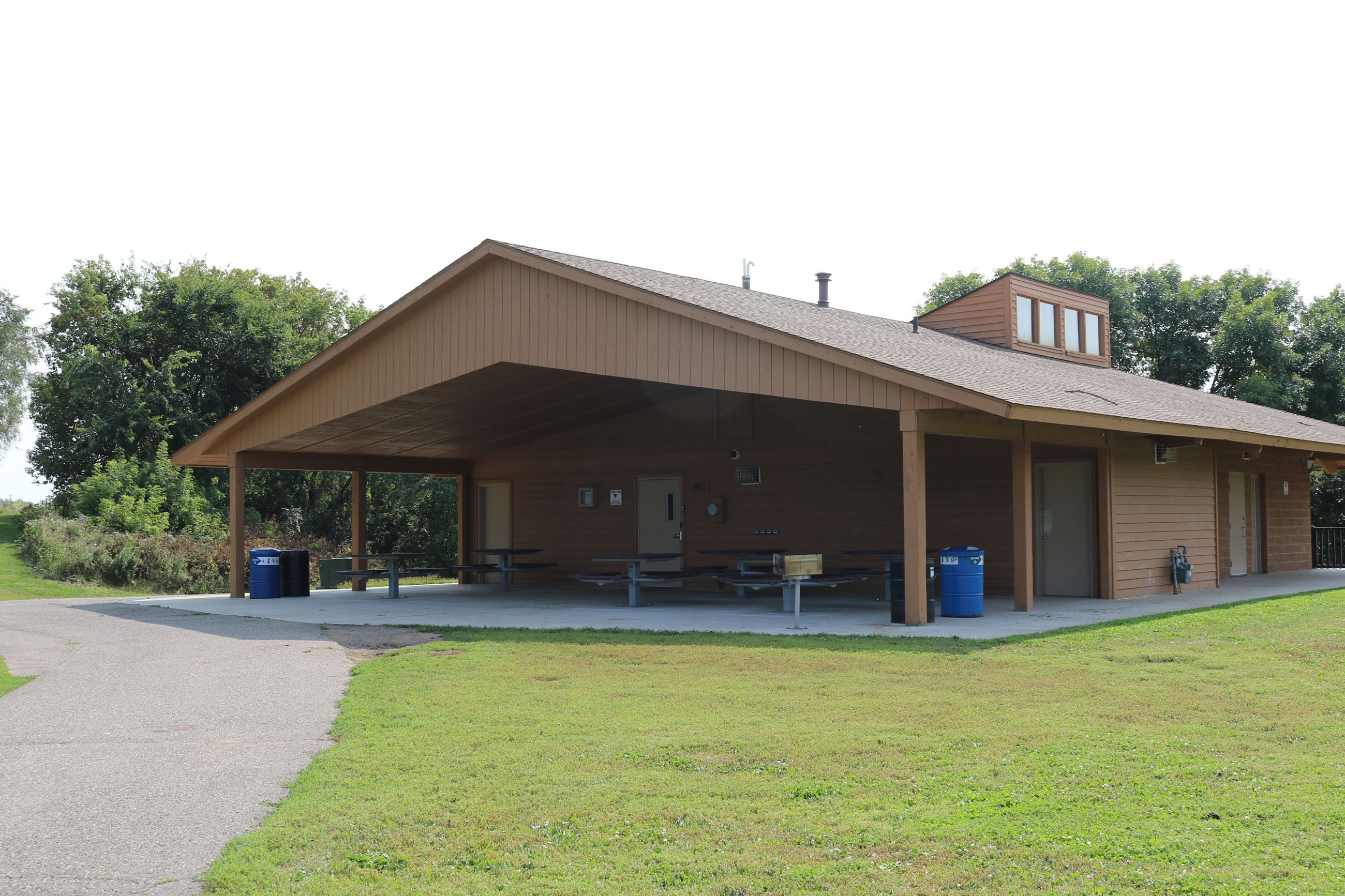 Brown park building with picnic tables under overhang. 