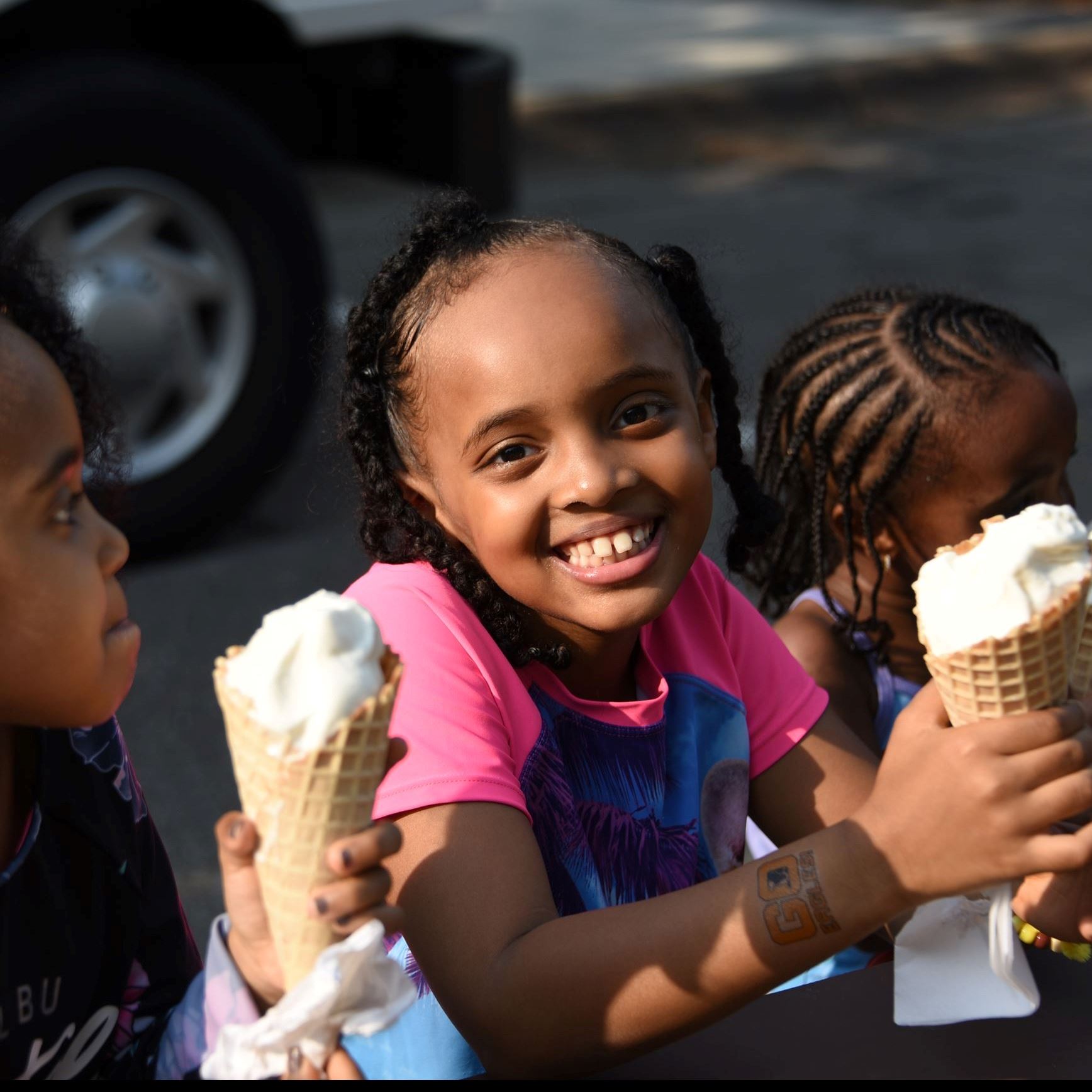 Little girl smiling with ice cream, sitting next to siblings