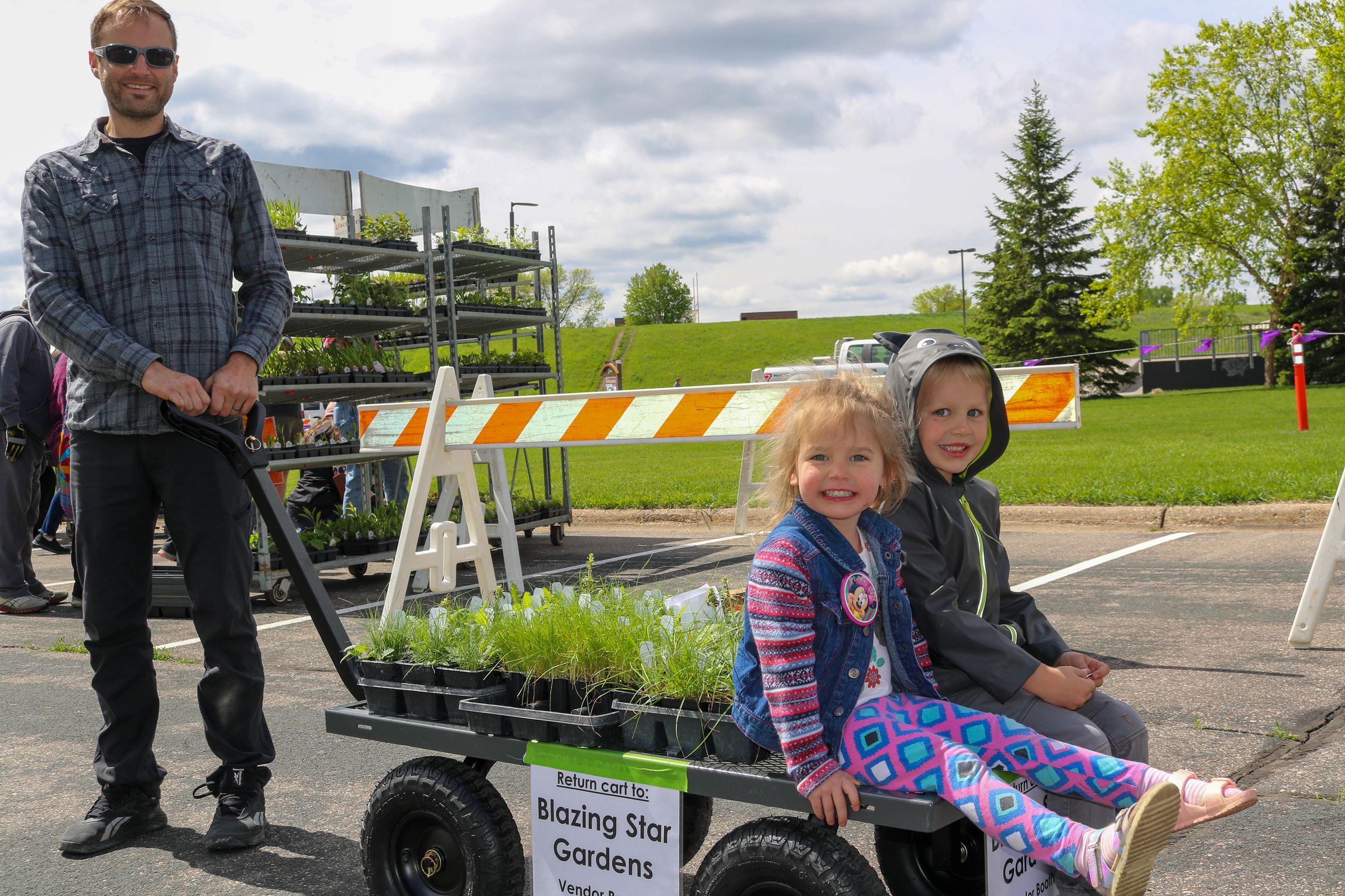 A dad pulling a wagon of plants and two kids
